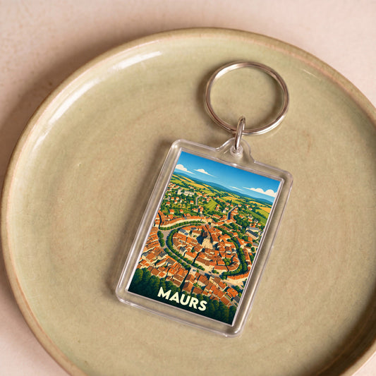 Porte-clés souvenir de la ville de Maurs avec une illustration stylisée vue du ciel.