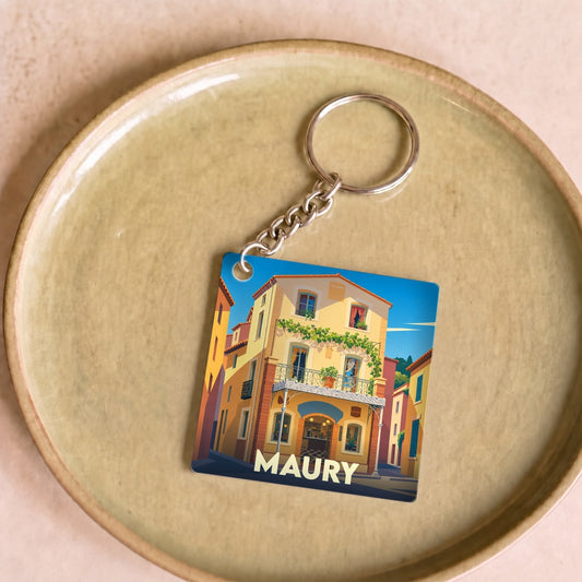 Porte-clés souvenir de la ville de Maury avec une illustration stylisée d'une maison de village colorée.