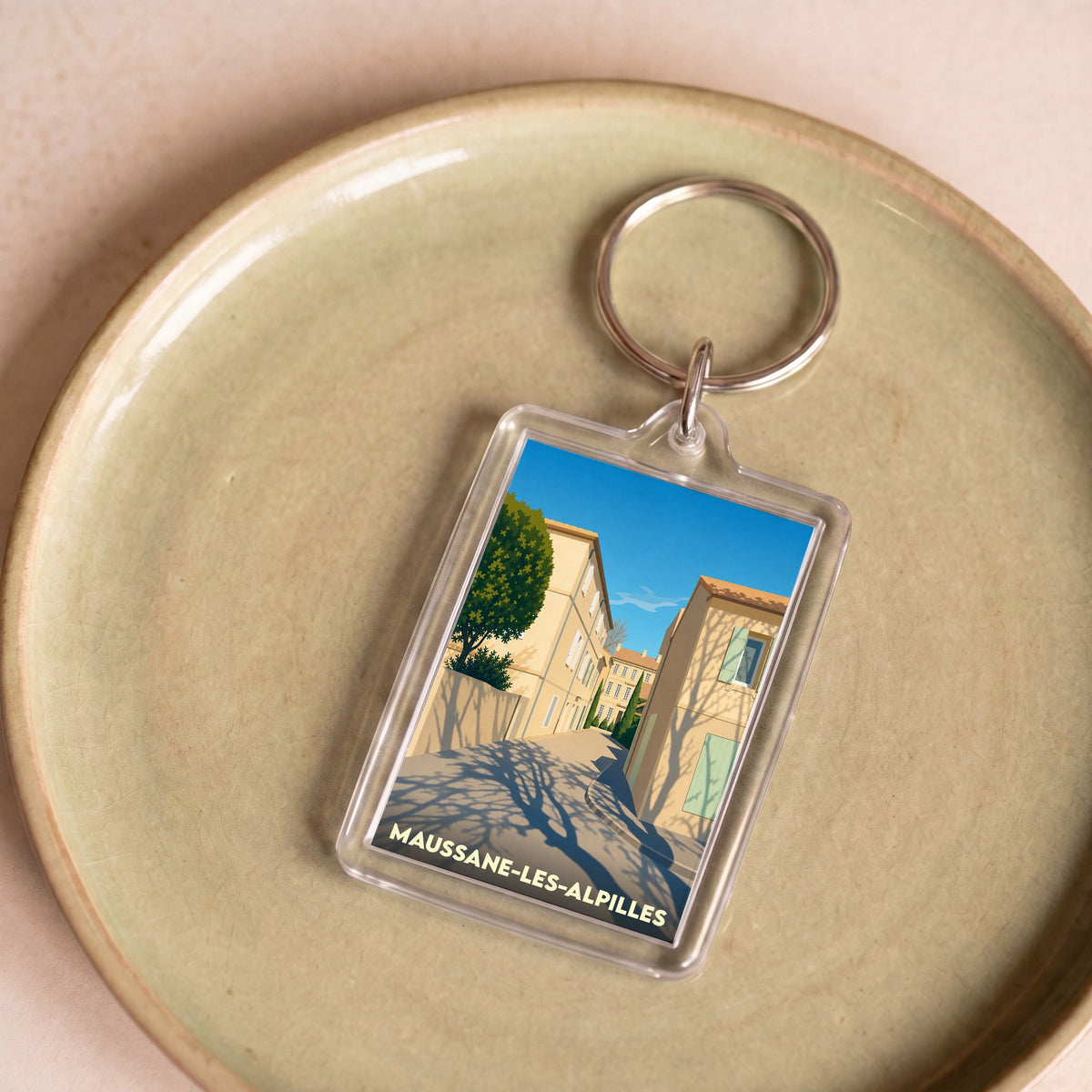 Porte-clés souvenir de la ville de Maussane-les-Alpilles avec une illustration stylisée.