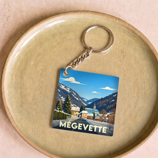 Porte-clés souvenir de la ville de Mégevette avec une illustration stylisée d'un paysage montagneux enneigé.