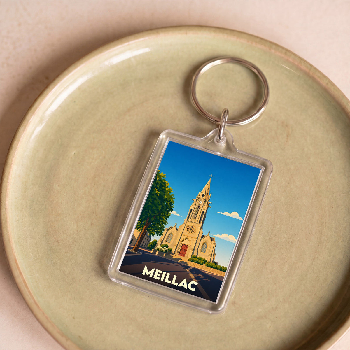 Porte-clés souvenir de la ville de Meillac avec une illustration stylisée de son église.
