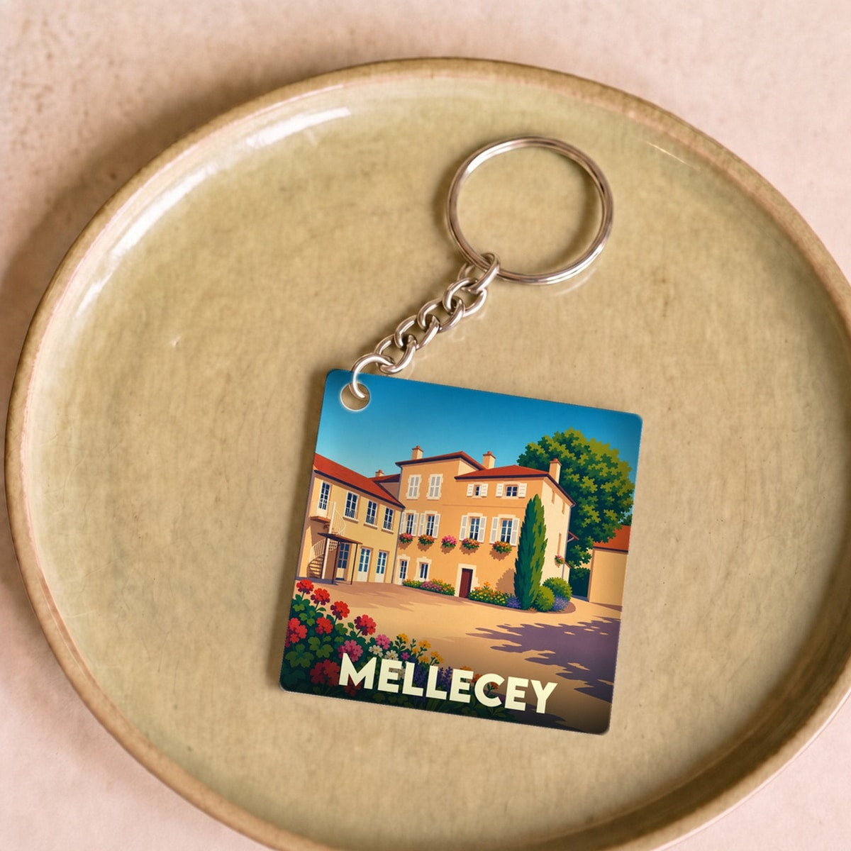 Porte-clés souvenir de la ville de Mellecey avec une illustration stylisée d'une demeure bourguignonne fleurie.