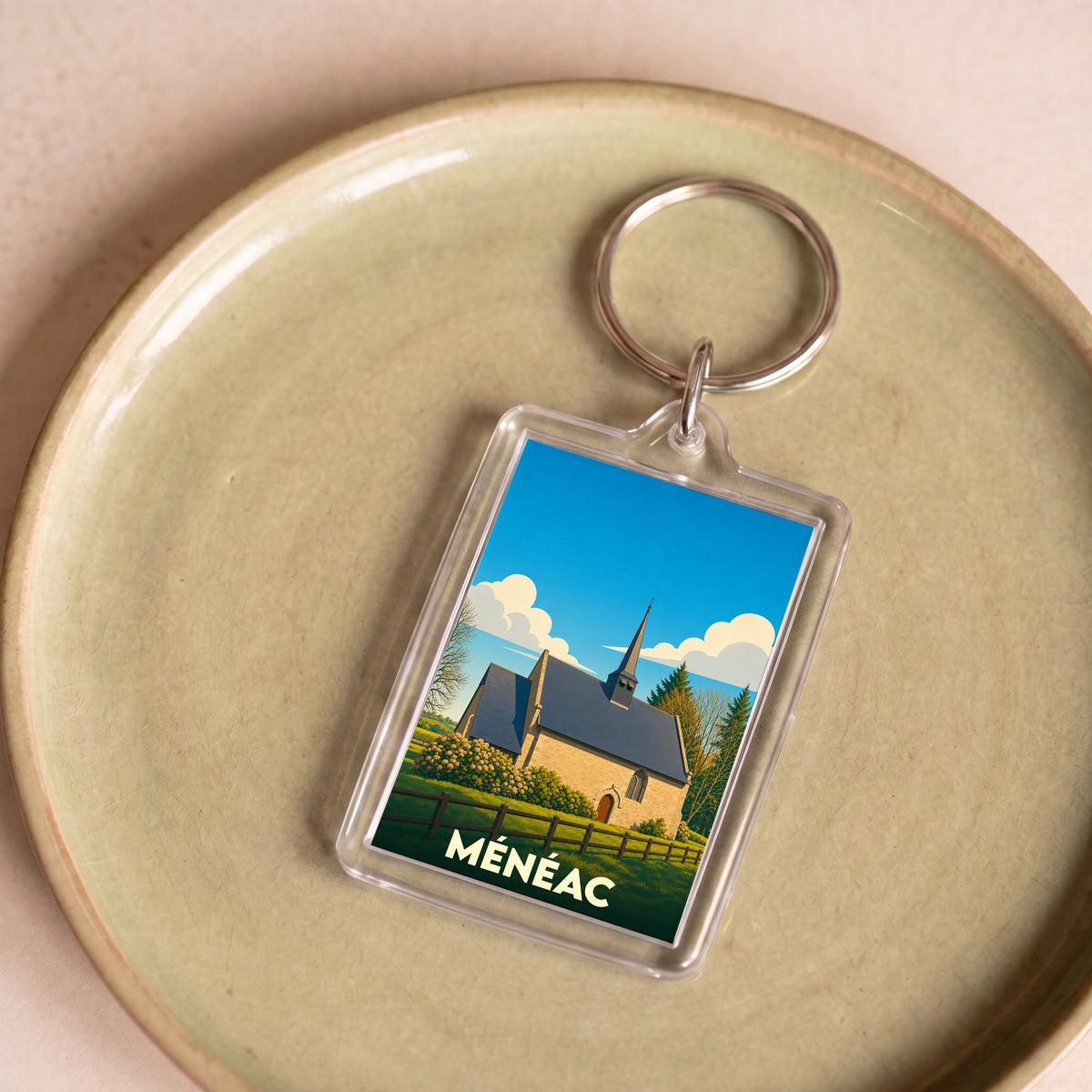 Porte-clés souvenir de la ville de Ménéac avec une illustration stylisée de sa chapelle.