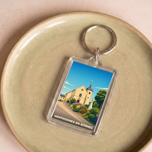 Porte-clés souvenir de la ville de Menthonnex-en-Bornes avec une illustration stylisée de son église.
