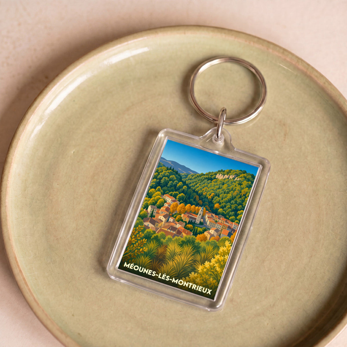 Porte-clés souvenir de la ville de Méounes-lès-Montrieux avec une illustration stylisée.