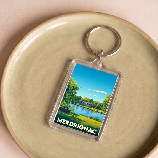 Porte-clés souvenir de la ville de Merdrignac avec une illustration stylisée d'un plan d'eau.