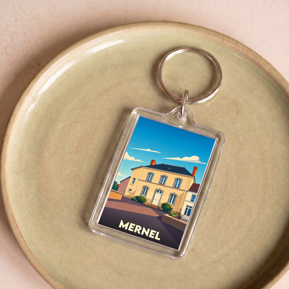 Porte-clés souvenir de la ville de Mernel avec une illustration stylisée d'un bâtiment local.