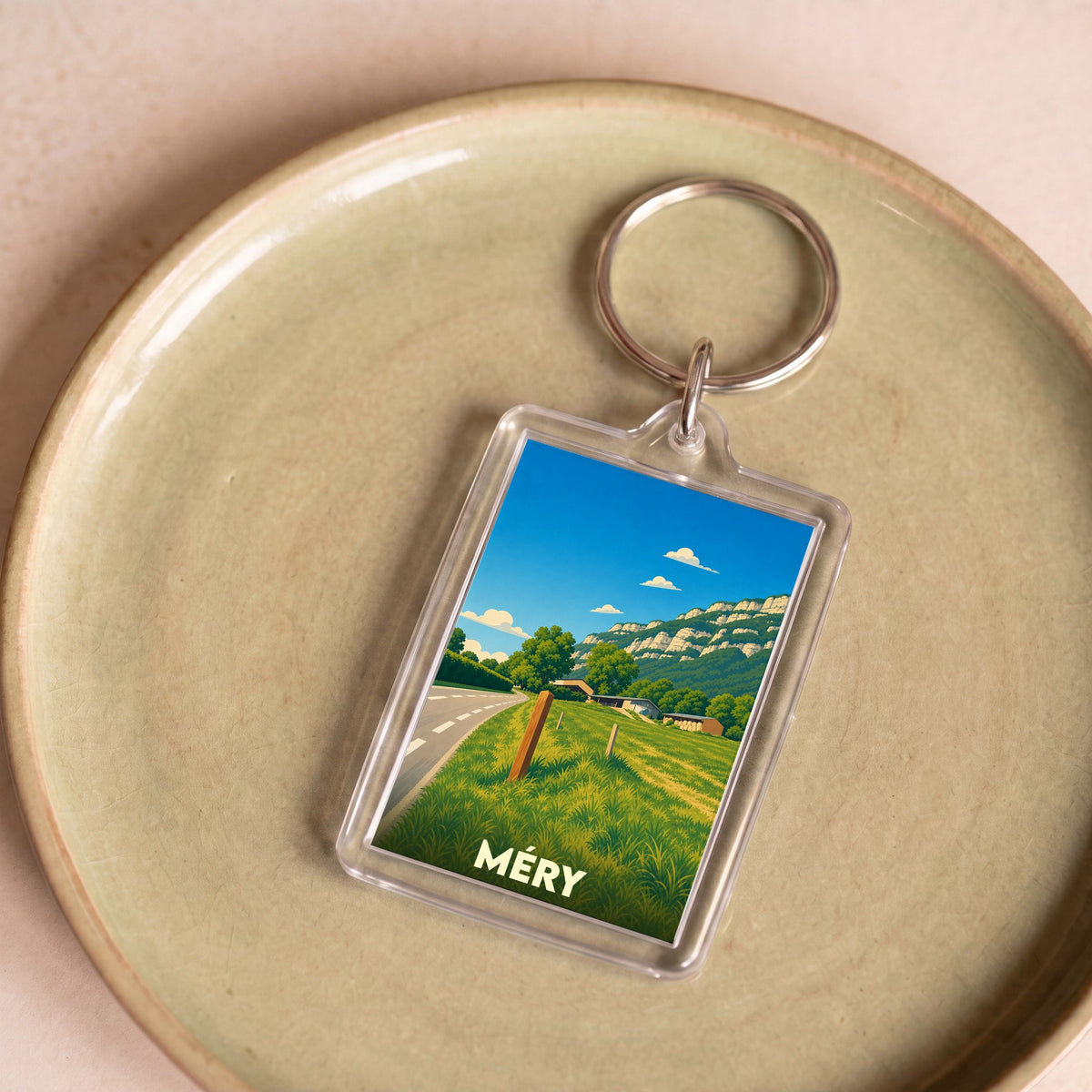 Porte-clés souvenir de la ville de Méry avec une illustration stylisée d'un paysage de campagne.