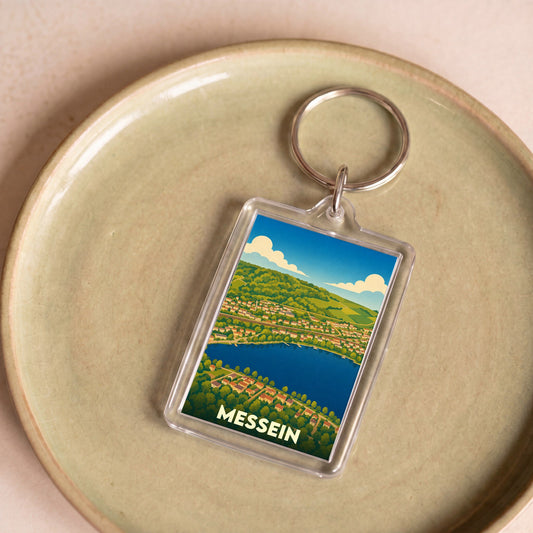 Porte-clés souvenir de la ville de Messein avec une illustration stylisée de ses paysages.
