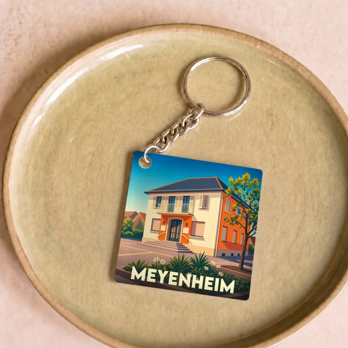 Porte-clés souvenir de la ville de Meyenheim avec une illustration stylisée d'un bâtiment local.