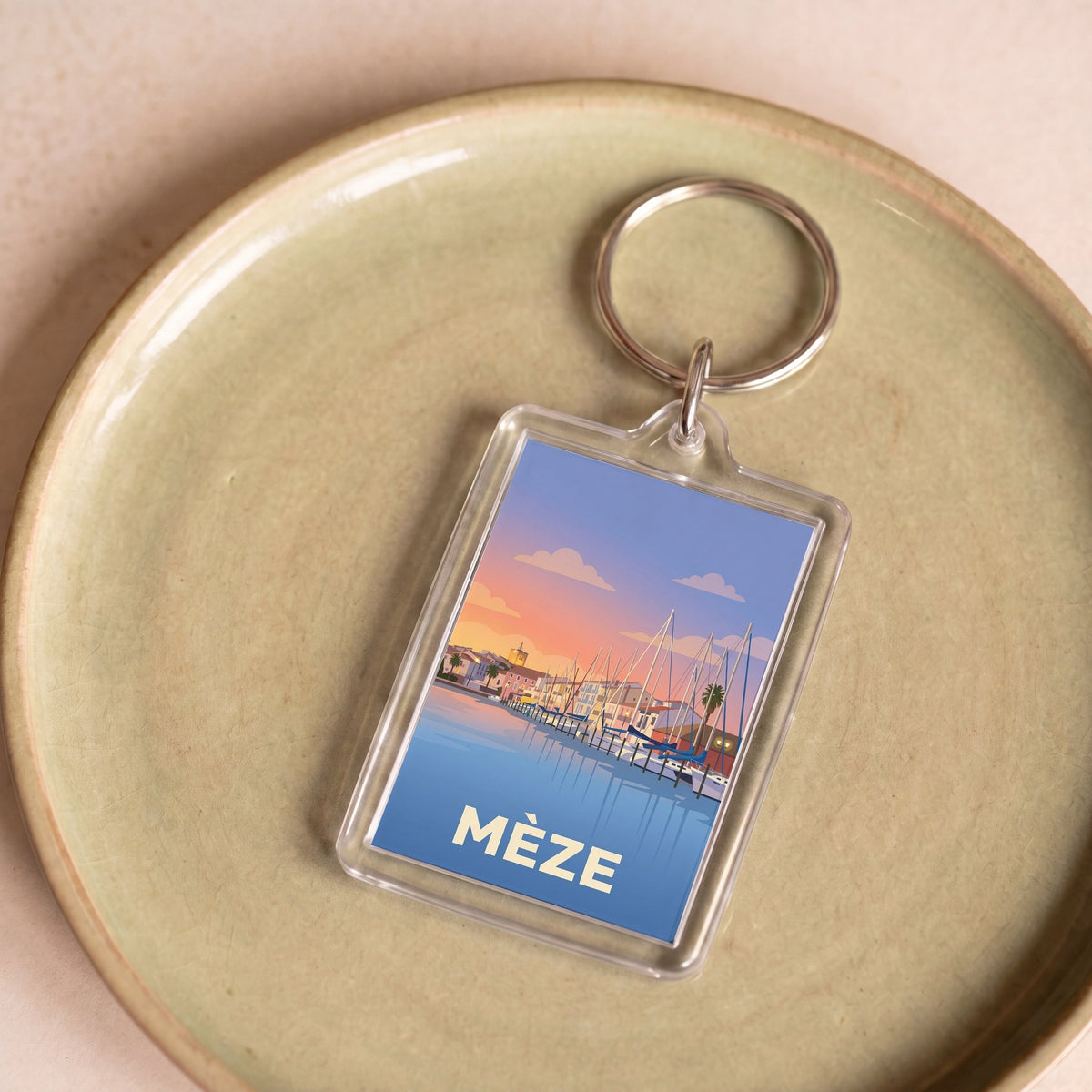 Porte-clés souvenir de la ville de Mèze avec une illustration stylisée.