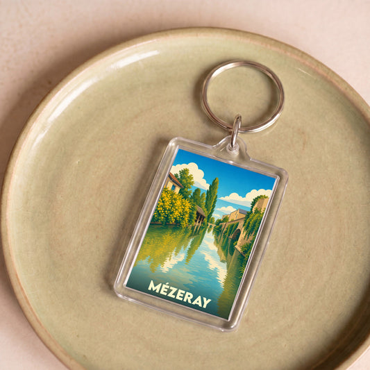 Porte-clés souvenir de la ville de Mézeray avec une illustration stylisée d'un cours d'eau bordé de verdure.