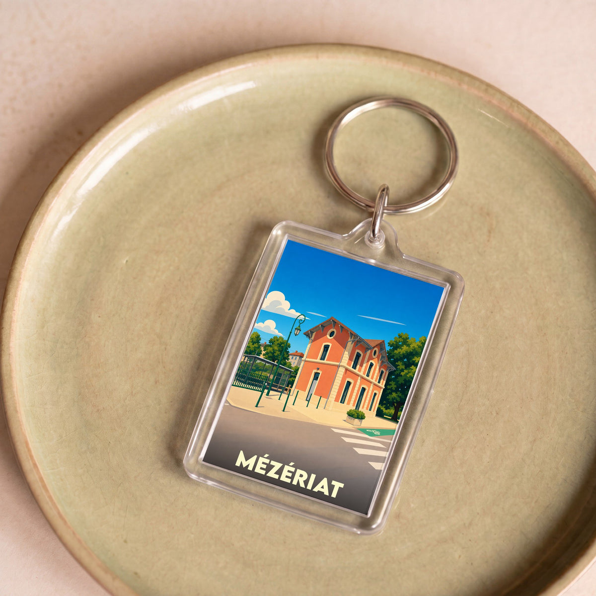 Porte-clés souvenir de la ville de Mézériat avec une illustration stylisée de sa gare.