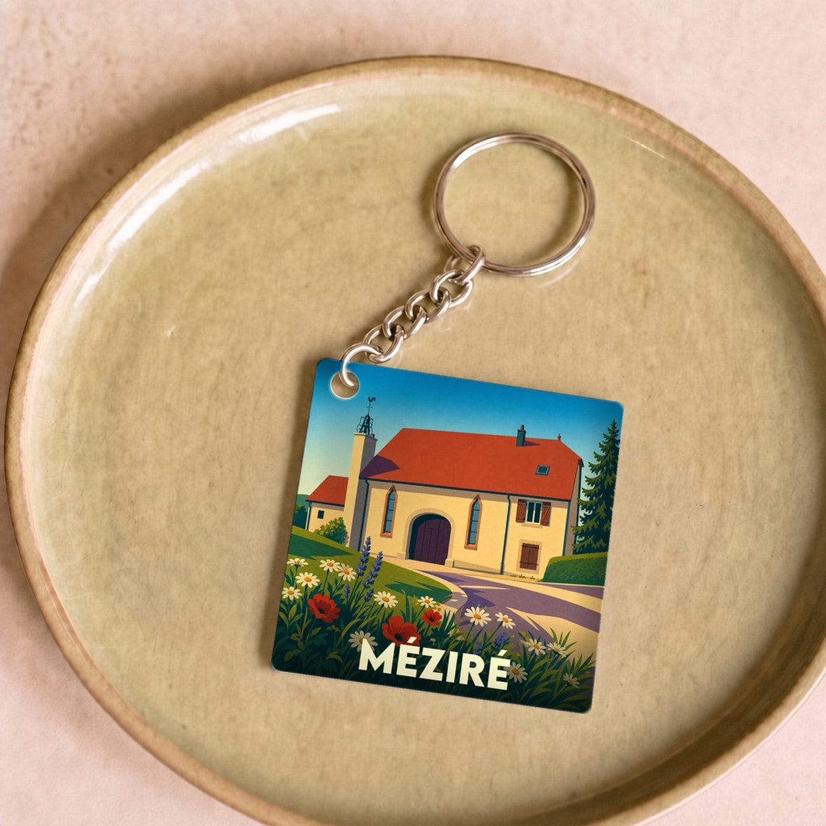 Porte-clés souvenir de la ville de Méziré avec une illustration stylisée d'un paysage champêtre.