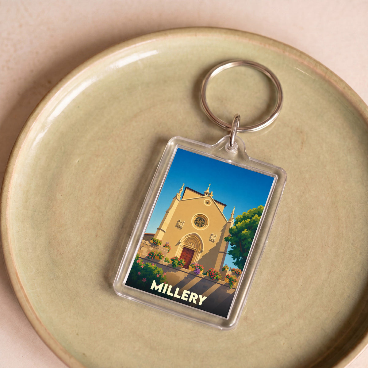 Porte-clés souvenir de la ville de Millery avec une illustration stylisée d'une église sous un ciel bleu.