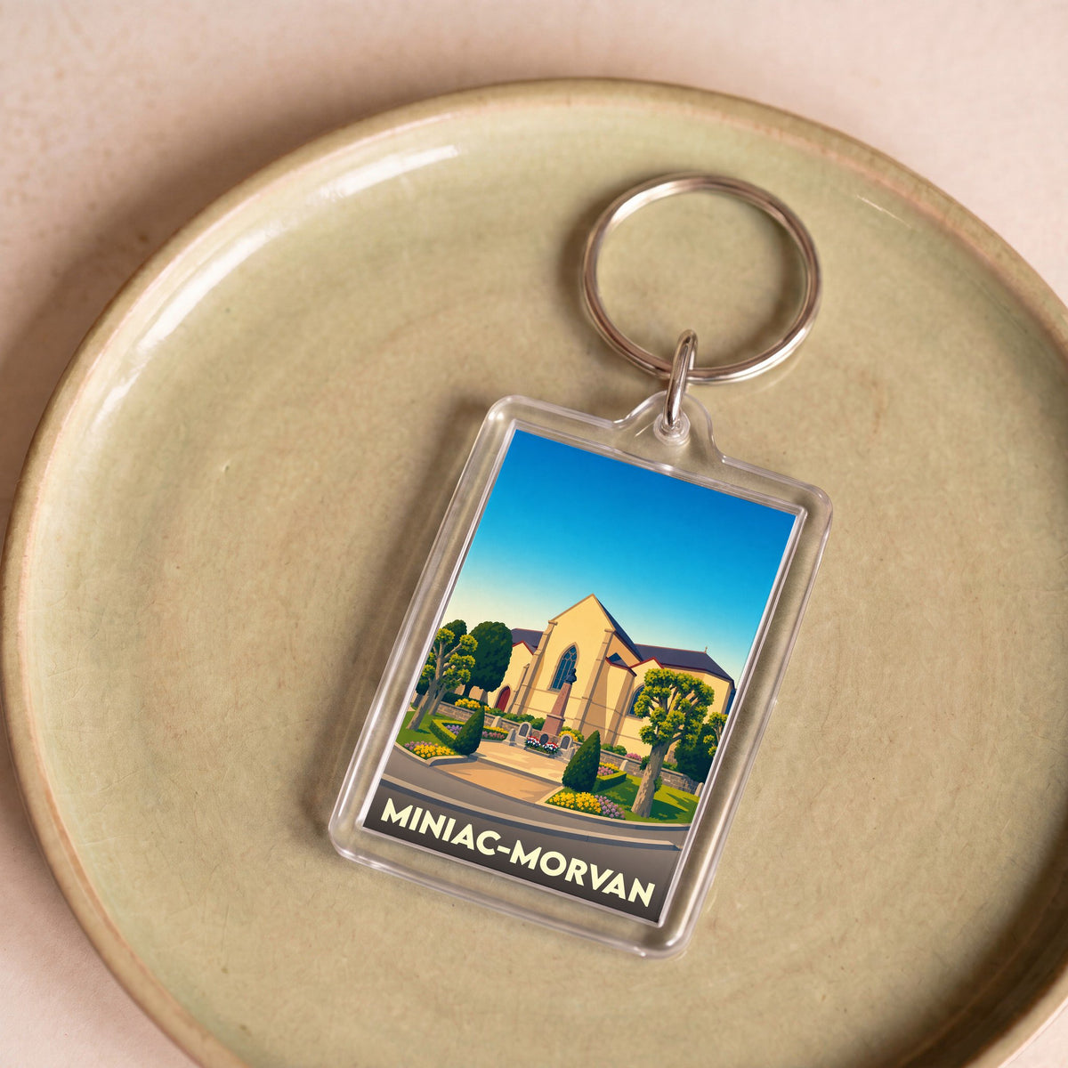 Porte-clés souvenir de la ville de Miniac-Morvan avec une illustration stylisée.