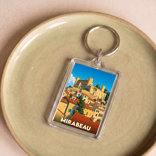 Porte-clés souvenir de la ville de Mirabeau avec une illustration stylisée d'un village provençal et son château.