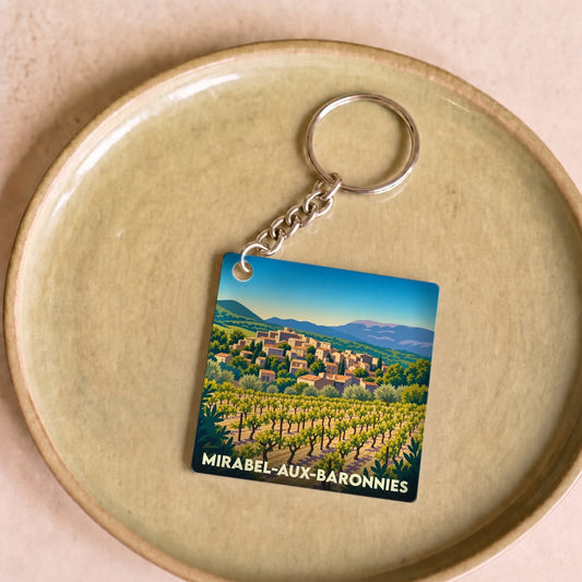 Porte-clés souvenir de la ville de Mirabel-aux-Baronnies avec une illustration stylisée d'un vignoble et d'un village perché.