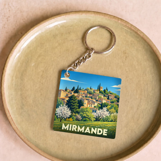 Porte-clés souvenir de la ville de Mirmande avec une illustration stylisée d'un village perché.