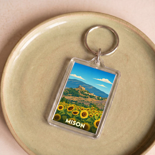 Porte-clés souvenir de la ville de Mison avec une illustration stylisée de tournesols et d'un village perché.