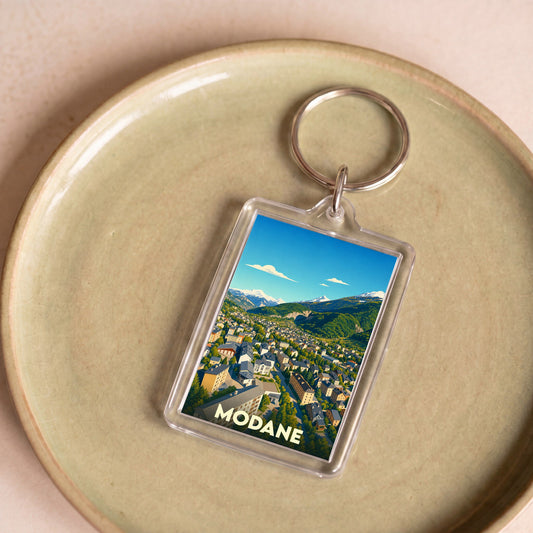 Porte-clés souvenir de la ville de Modane avec une illustration stylisée d'un paysage montagneux.