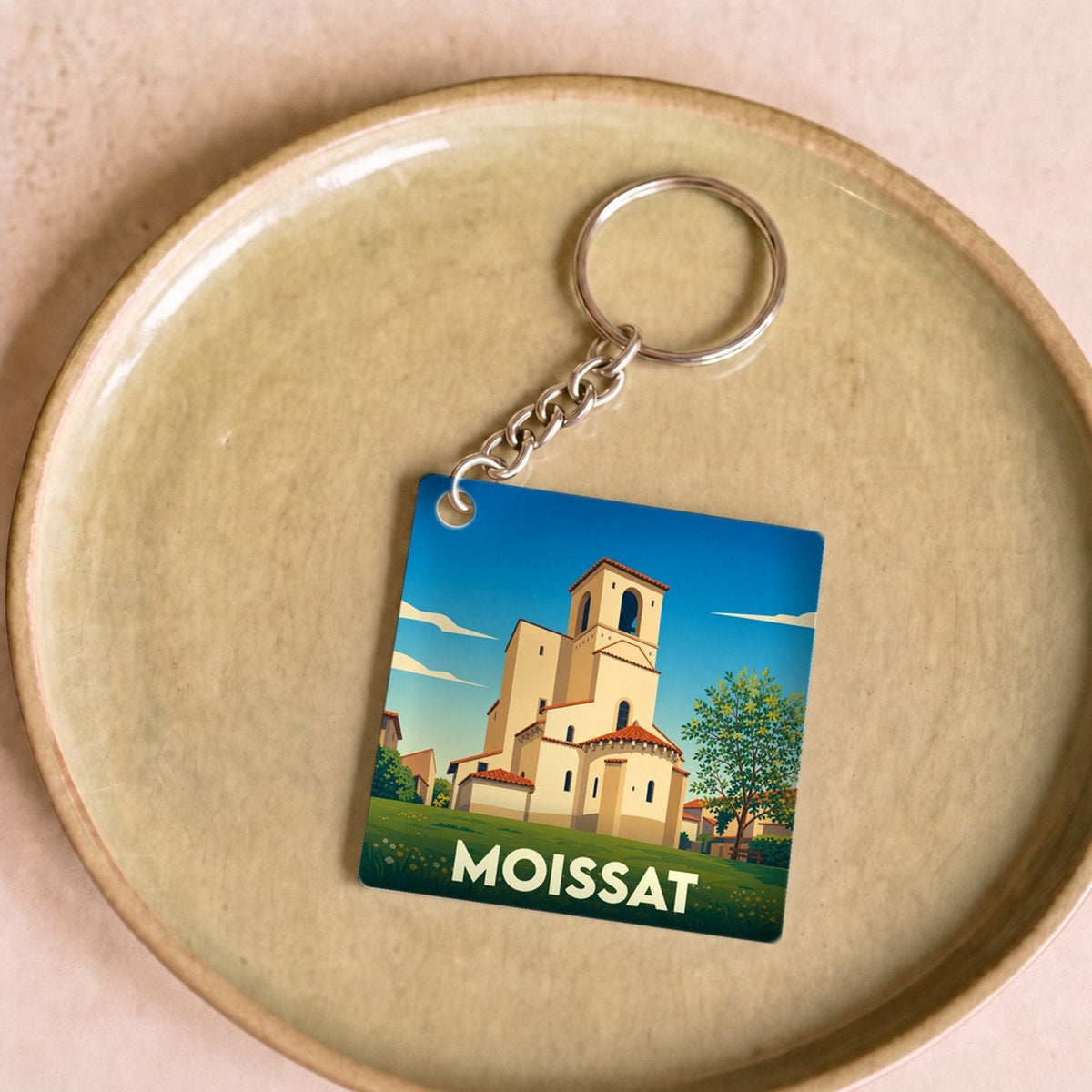 Porte-clés souvenir de la ville de Moissat avec une illustration stylisée de son église.