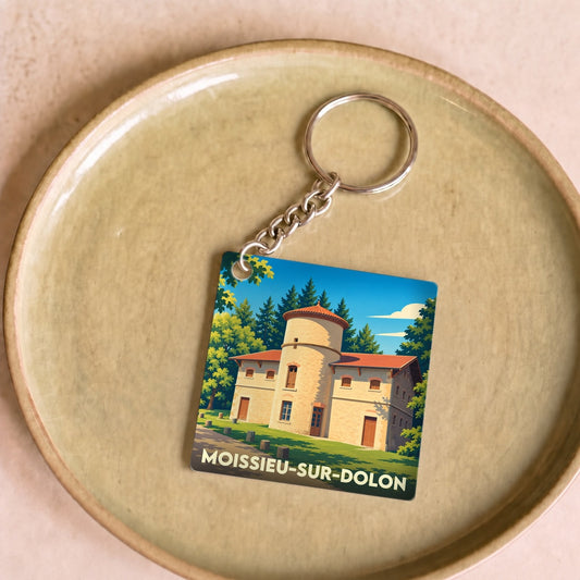 Porte-clés souvenir de la ville de Moissieu-sur-Dolon avec une illustration stylisée d'un bâtiment à tour ronde.