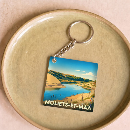 Porte-clés souvenir de la ville de Moliets-et-Maa avec une illustration stylisée de son paysage côtier.