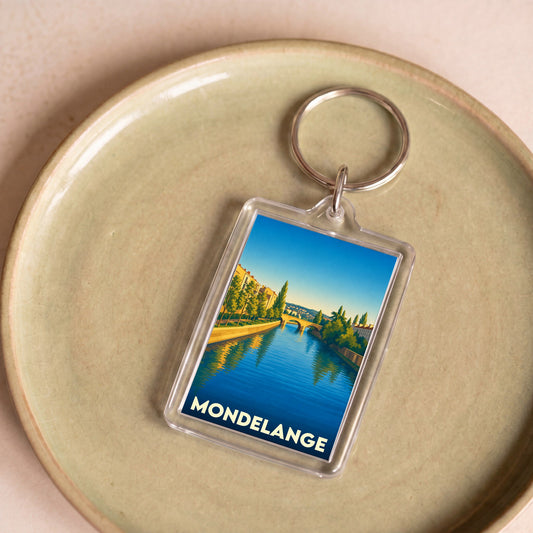 Porte-clés souvenir de la ville de Mondelange avec une illustration stylisée d'un paysage fluvial.