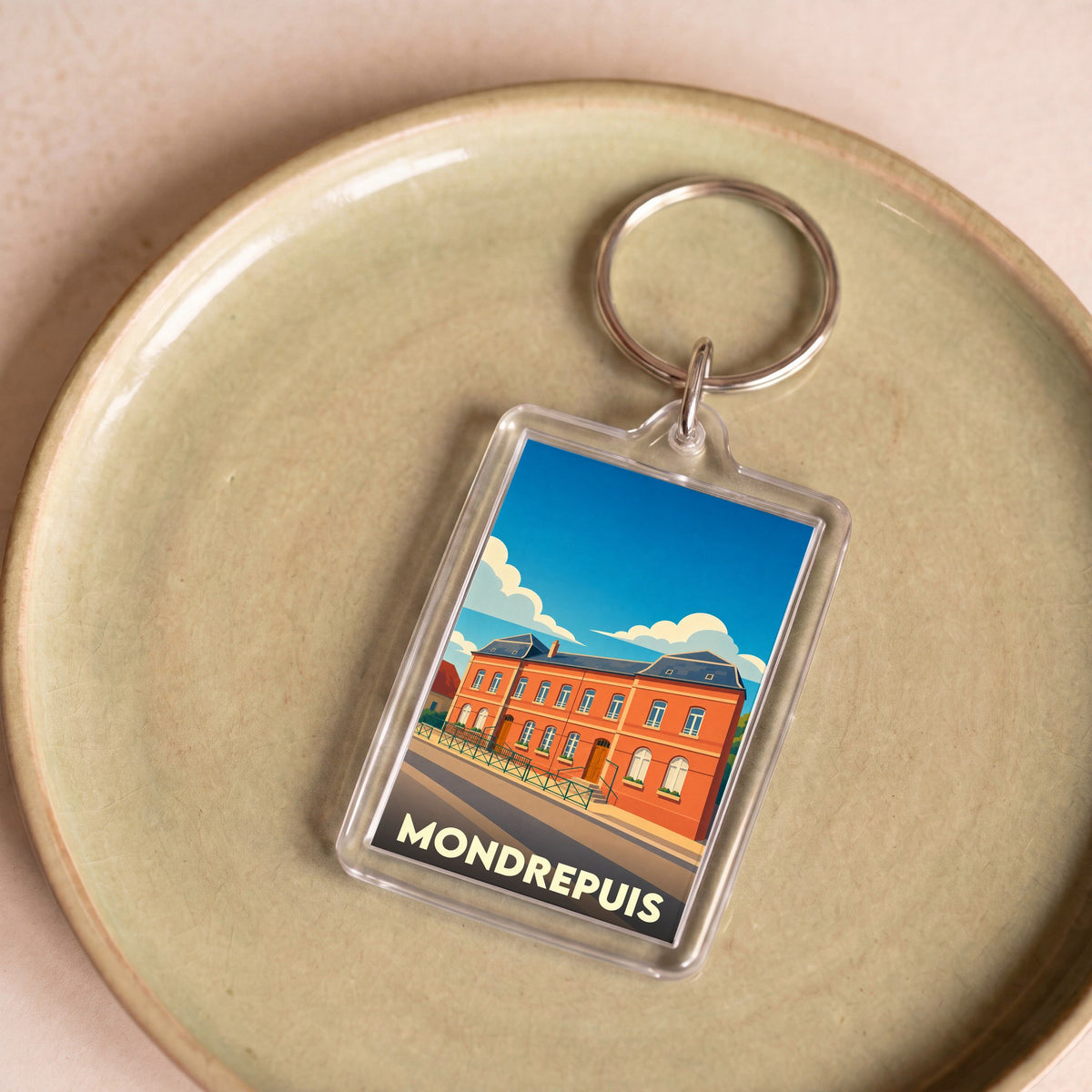 Porte-clés souvenir de la ville de Mondrepuis avec une illustration stylisée.