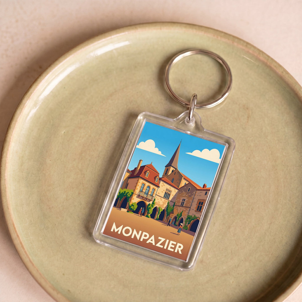 Porte-clés souvenir de la ville de Monpazier avec une illustration stylisée.