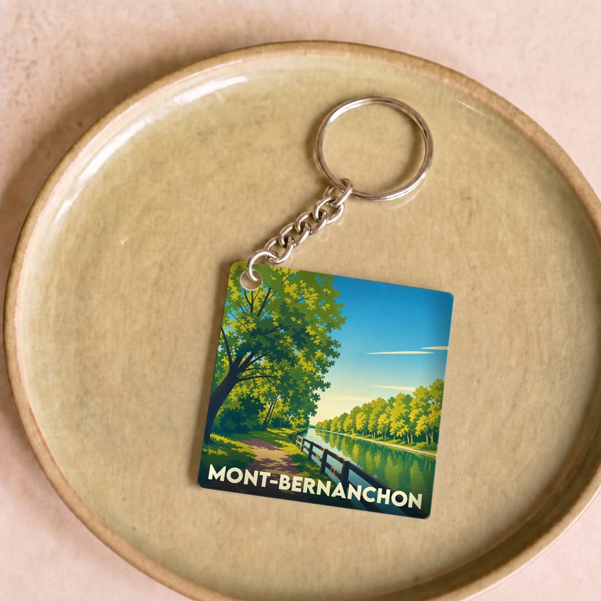 Porte-clés souvenir de la ville de Mont-Bernanchon avec une illustration stylisée d'un canal arboré.
