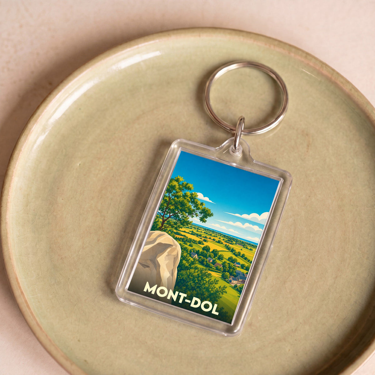 Porte-clés souvenir de la ville de Mont-Dol avec une illustration stylisée d'un paysage panoramique.