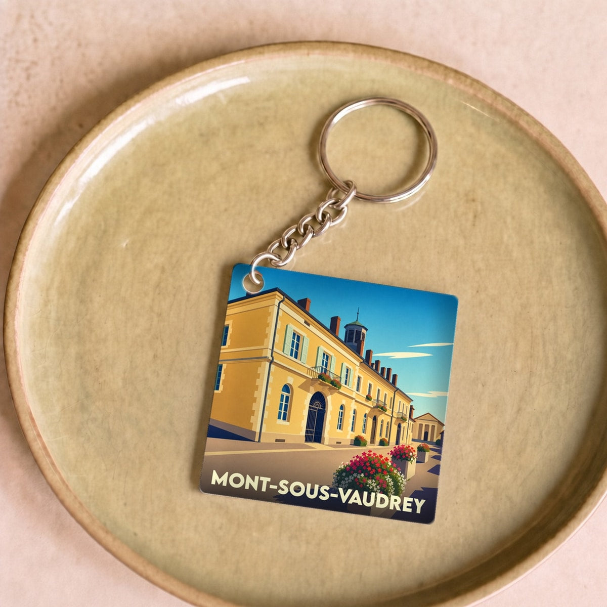 Porte-clés souvenir de la ville de Mont-sous-Vaudrey avec une illustration stylisée.