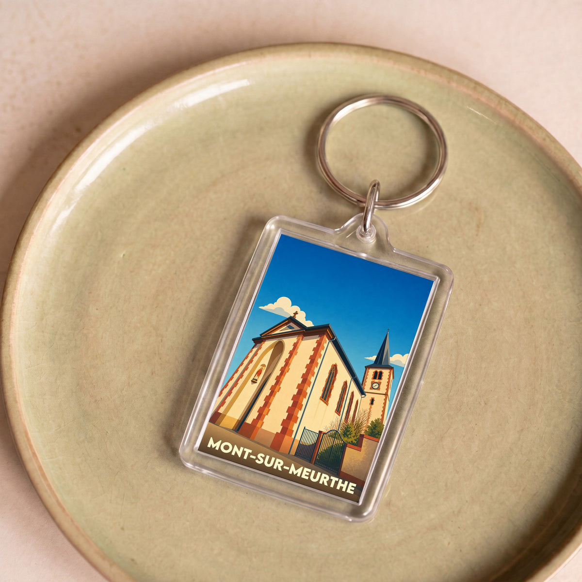 Porte-clés souvenir de la ville de Mont-sur-Meurthe avec une illustration stylisée de son église.