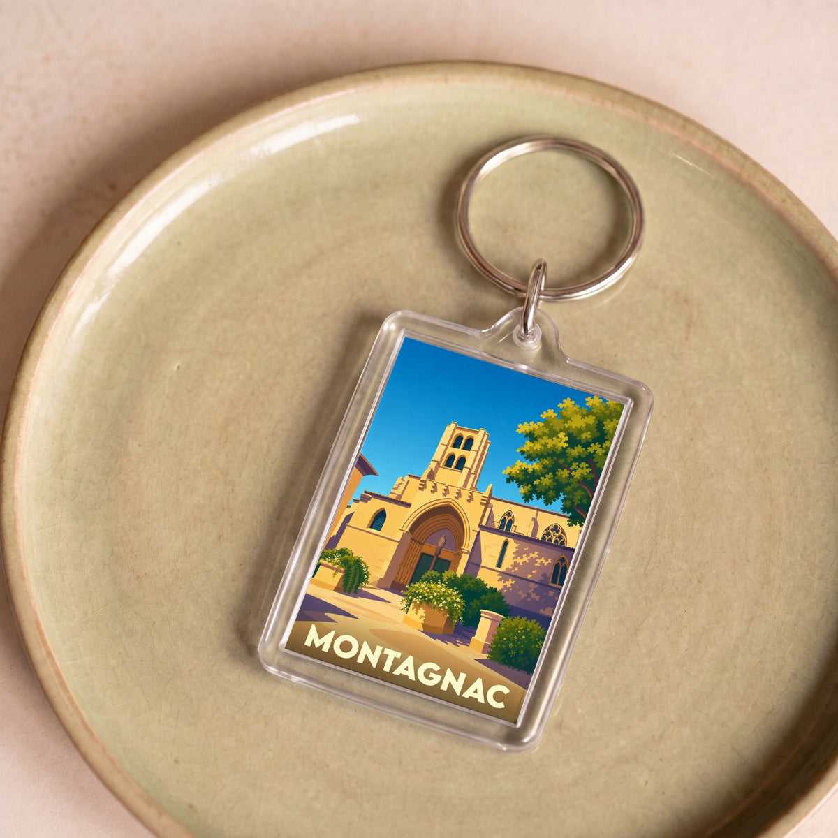 Porte-clés souvenir de la ville de Montagnac avec une illustration stylisée de son église.