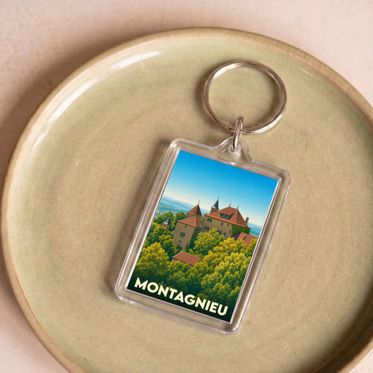 Porte-clés souvenir de la ville de Montagnieu avec une illustration stylisée d'un château entouré de verdure.