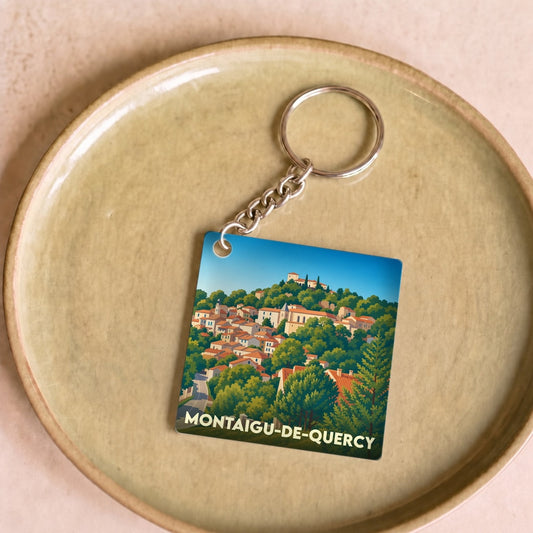 Porte-clés souvenir de Montaigu-de-Quercy avec une illustration stylisée du village perché.