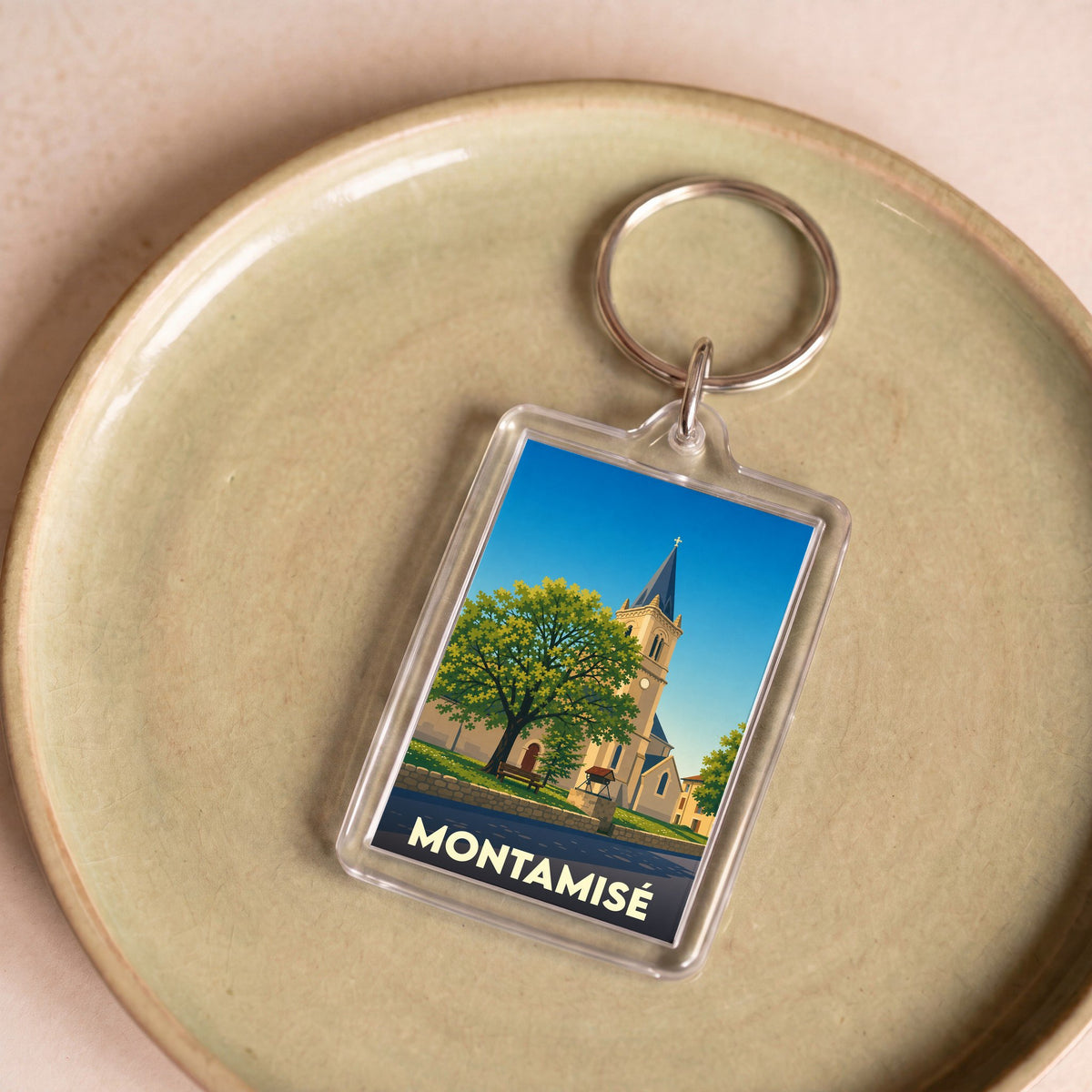 Porte-clés souvenir de la ville de Montamisé avec une illustration stylisée d'une église et d'un grand arbre.