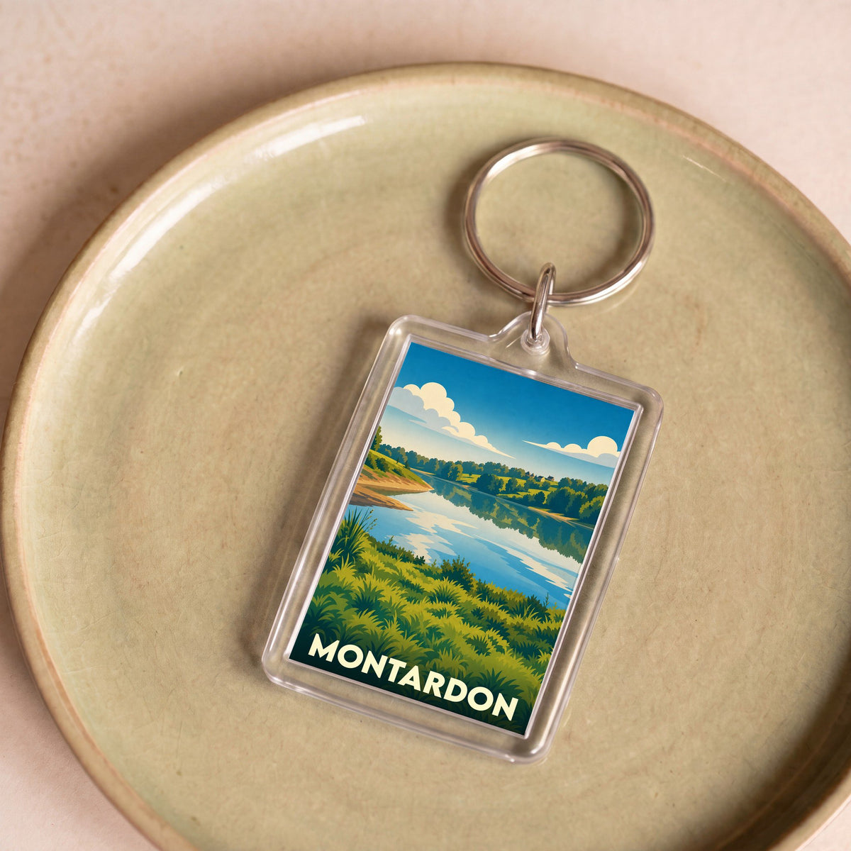 Porte-clés souvenir de la ville de Montardon avec une illustration stylisée de paysage lacustre.