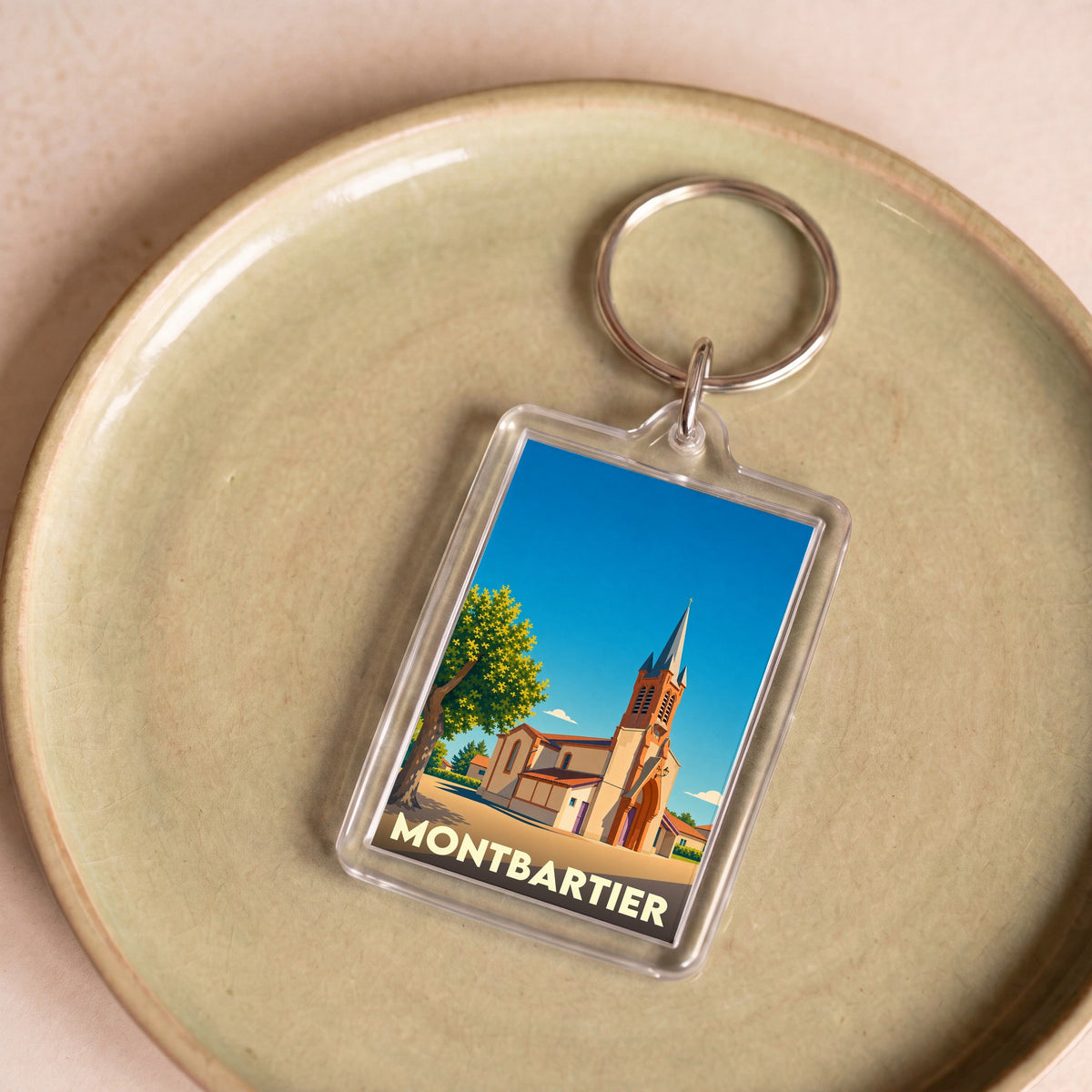 Porte-clés souvenir de la ville de Montbartier avec une illustration stylisée de son église.