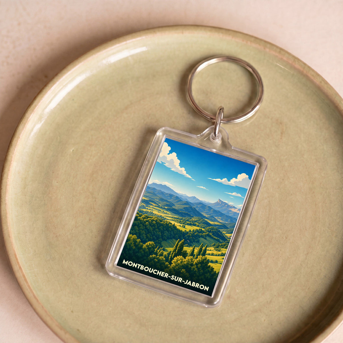 Porte-clés souvenir de la ville de Montboucher-sur-Jabron avec une illustration stylisée de paysages vallonnés.