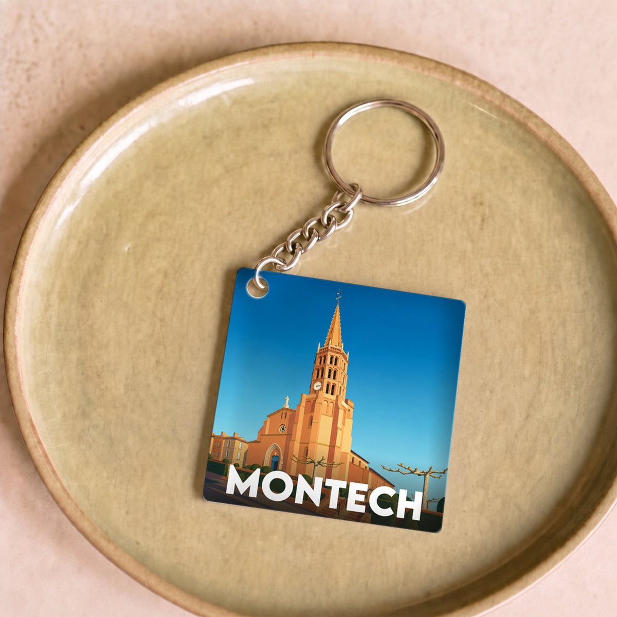 Porte-clés souvenir de la ville de Montech avec une illustration stylisée de son église.