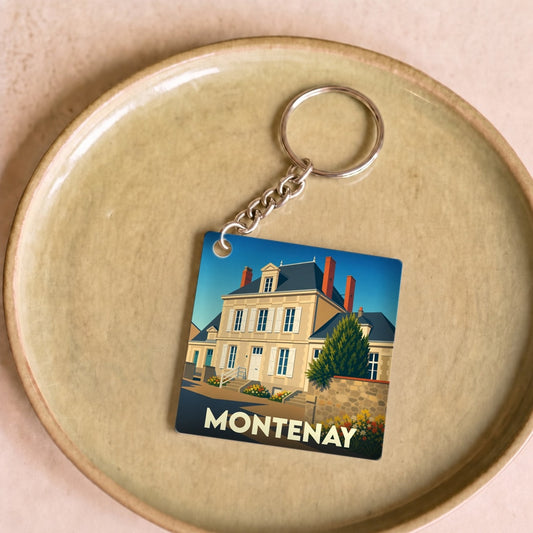 Porte-clés souvenir de la ville de Montenay avec une illustration stylisée d'une demeure traditionnelle.