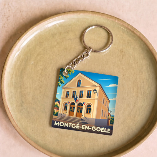 Porte-clés souvenir de la ville de Montgé-en-Goële avec une illustration stylisée de sa mairie.