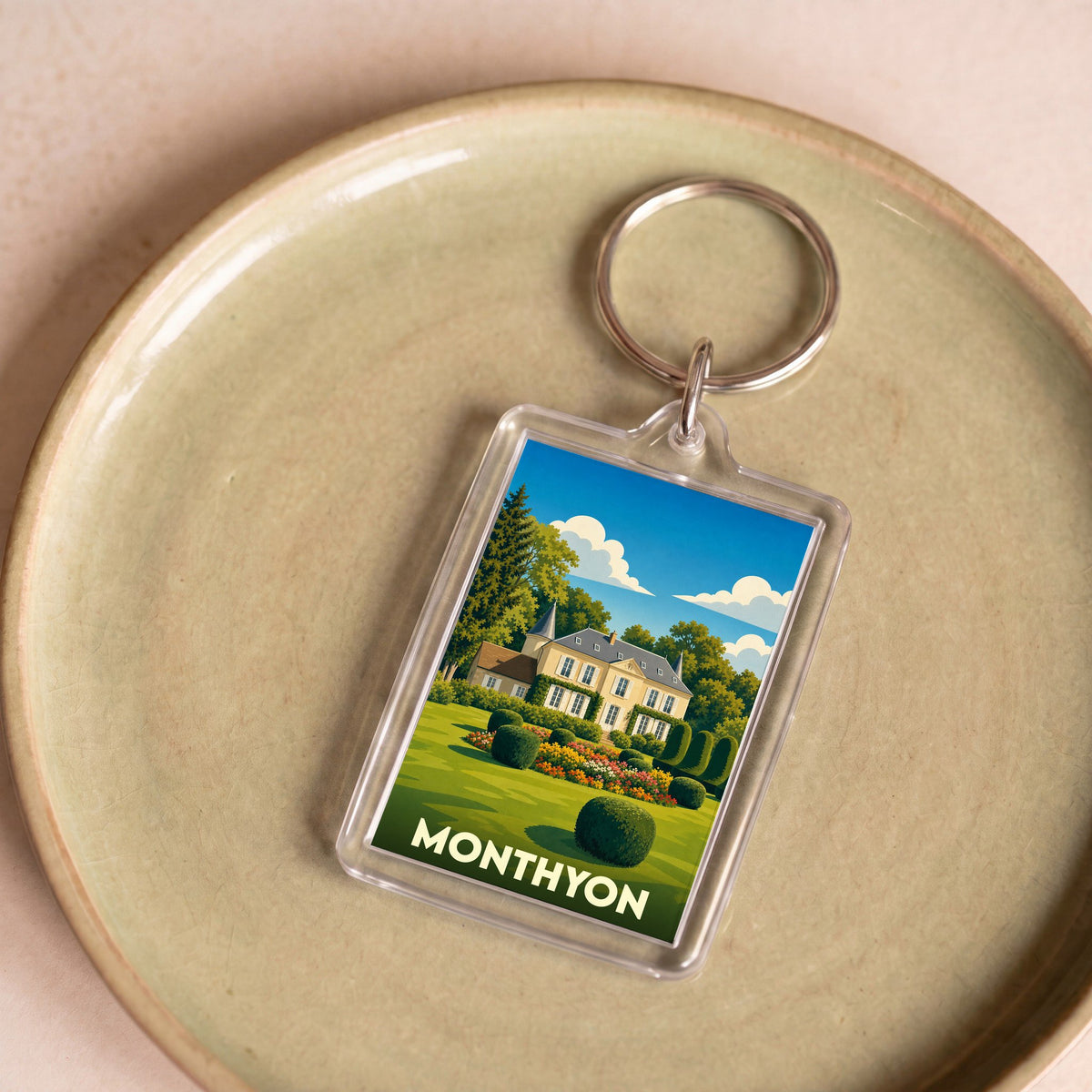 Porte-clés souvenir de la ville de Monthyon avec une illustration stylisée d'un domaine fleuri.