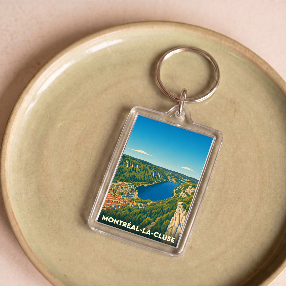Porte-clés souvenir de la ville de Montréal-la-Cluse avec une illustration stylisée du lac de Nantua.