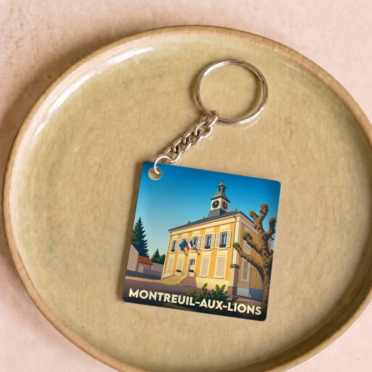 Porte-clés souvenir de la ville de Montreuil-aux-Lions avec une illustration stylisée de sa mairie.