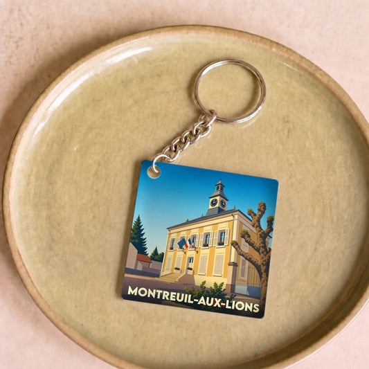 Porte-clés souvenir de la ville de Montreuil-aux-Lions avec une illustration stylisée de sa mairie.