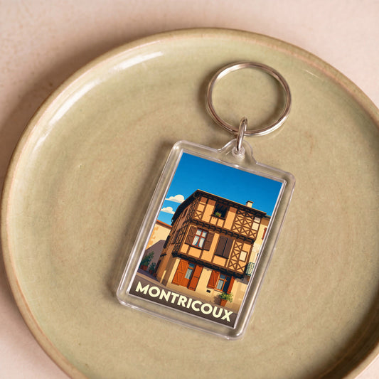 Porte-clés souvenir de la ville de Montricoux avec une illustration stylisée d'une maison à colombages.